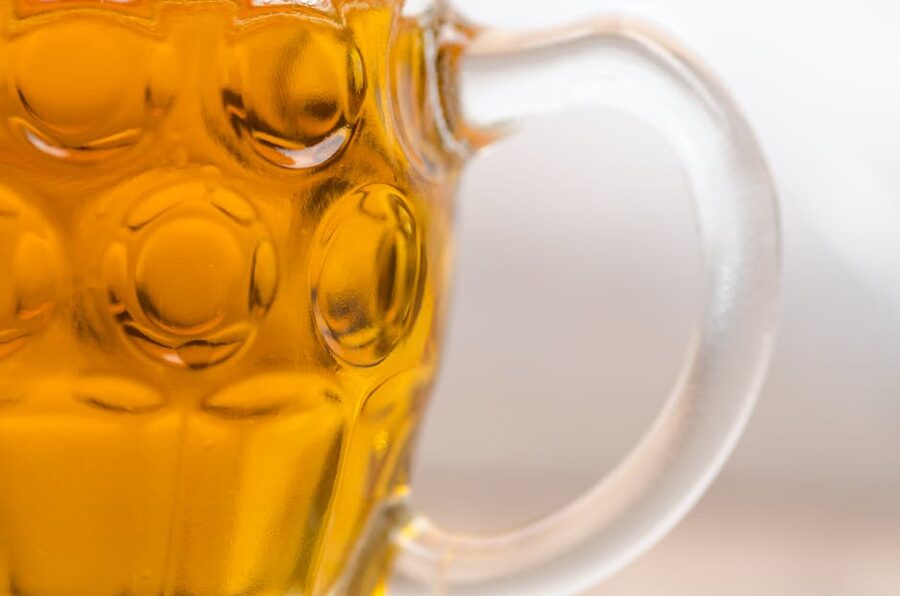 Close-up of a textured glass mug filled with amber wheat beer