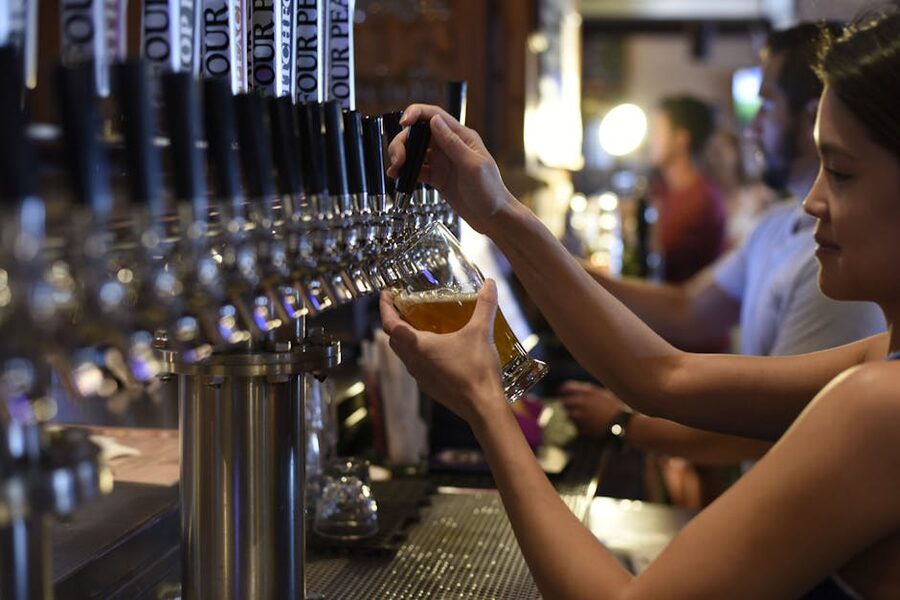 Bartender pouring craft beer from a long row of taps at a brewpub