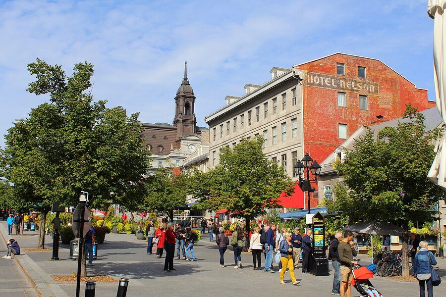Place Jacques-Cartier on a summer day with terrasses, planters, and the old Hotel Nelson sign on a brick wall