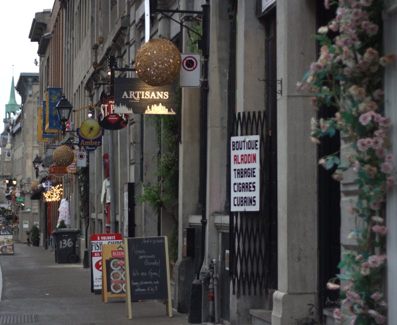 Old Montreal shopfronts on rue Saint-Paul with vintage signs and flowers spilling from a balcony